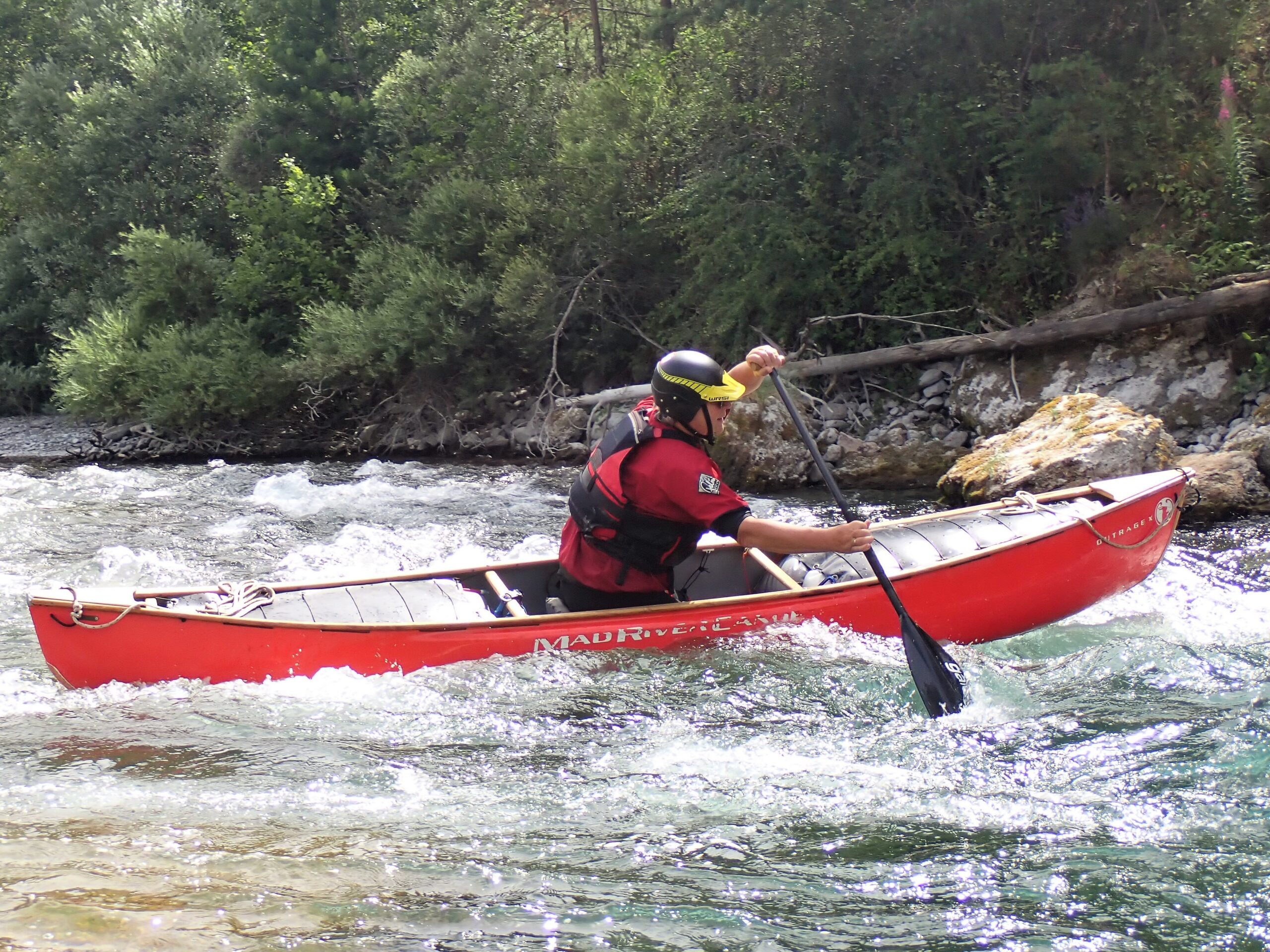 Deelnemer open canadees varen in een stroomversnelling tijdens een kajakcursus
